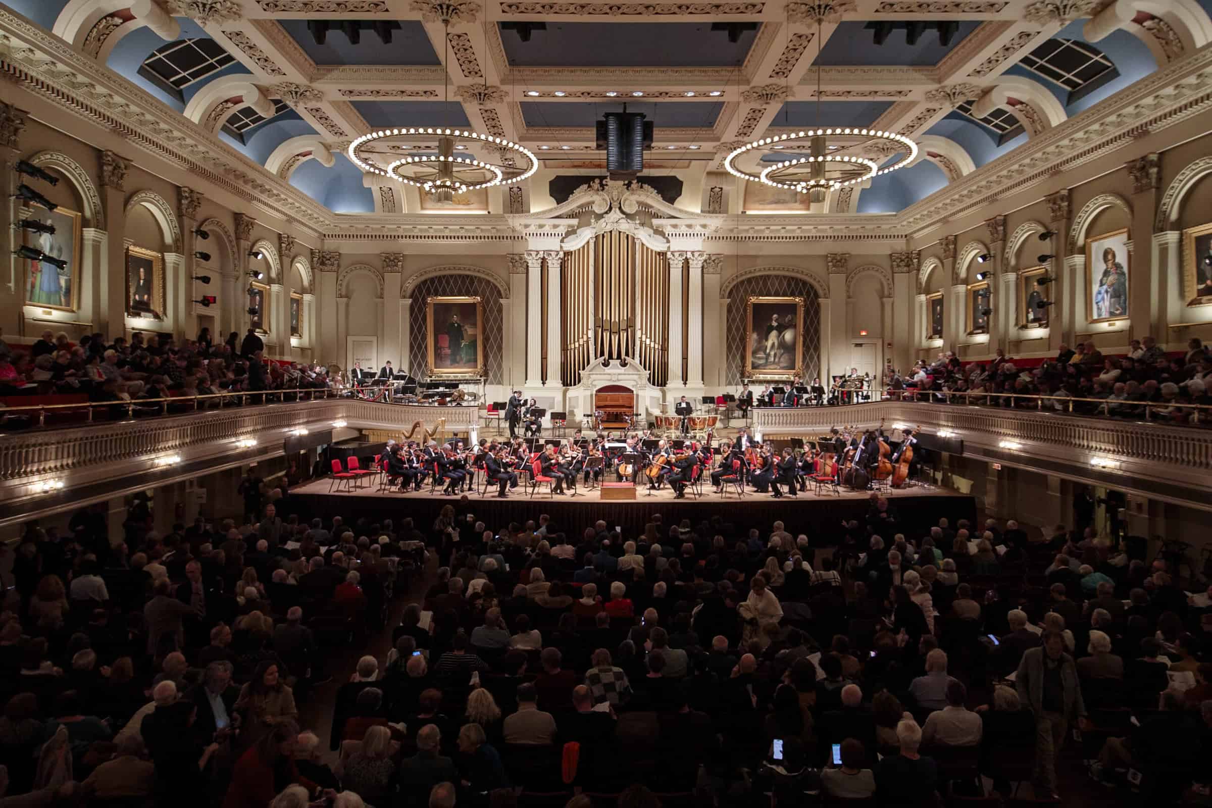 A large orchestra on stage in a large hall